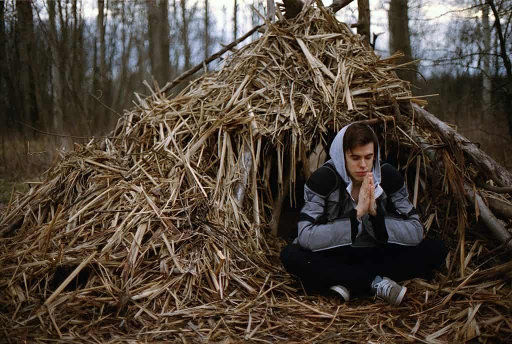 young man praying beside haystack