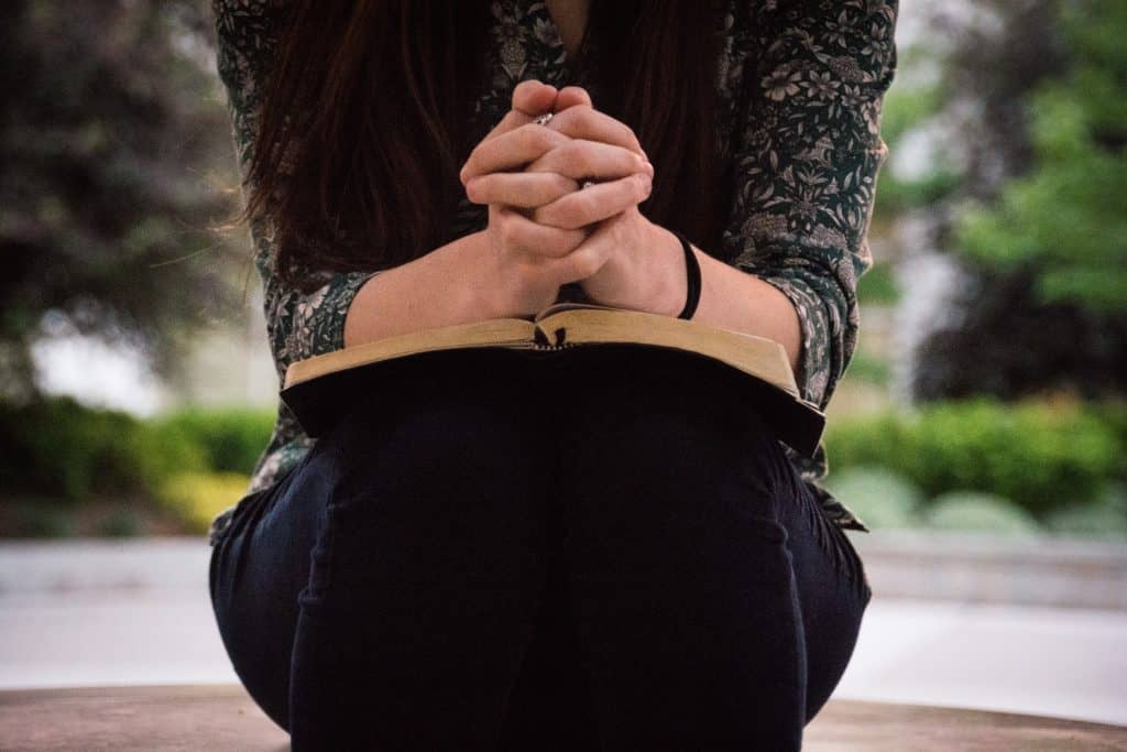 woman praying with open Bible