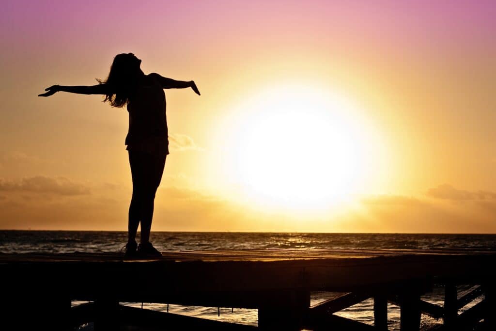 woman looking up with arms outstretched